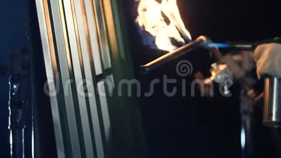 用丁烷火炬燃烧灰色金属壁板在黑暗中特写镜头视频的预览图