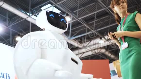 有机器人的漂亮女孩现代机器人技术机器人看着镜头对准人机器人展示了视频的预览图