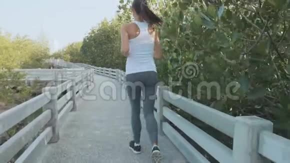年轻女子在红树林森林小径上慢跑斯泰迪加姆慢镜头视频的预览图