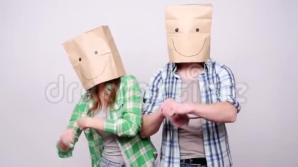 一对头上戴着纸袋的年轻夫妇高兴地跳舞视频的预览图