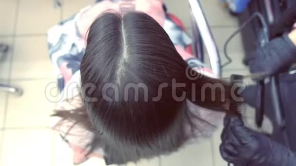 美容师在美容院用发钳给美女扎黑棕色头发头发特写视频的预览图