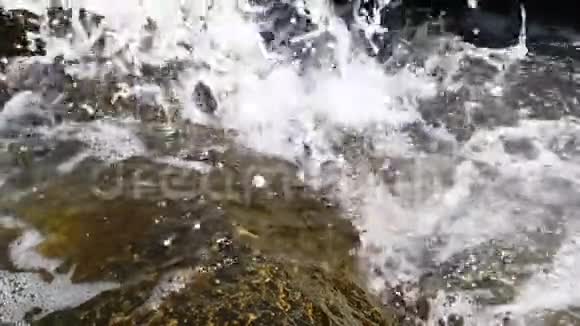 一股泡沫的海浪落在岩石上视频的预览图