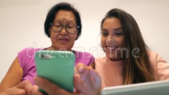 年轻的混血女孩用手机向她的资深亚洲母亲展示一些东西4k视频的预览图
