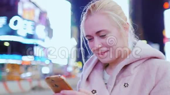 年轻女子穿着粉色外套在电话里打短信它应该在纽约曼哈顿时代广场视频的预览图