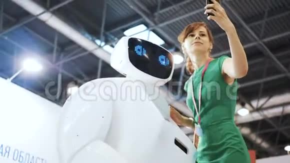 积极的女人用机器人做自拍女孩用机器人自拍漂亮女人在机器人后面重复动作视频的预览图