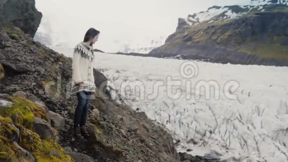 年轻的旅行妇女穿过山脉中的岩石探索冰岛的Vatnajokull冰川泻湖视频的预览图