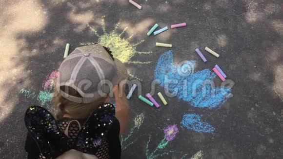 一个小女孩在沥青上画粉笔孩子在公园里晒太阳视频的预览图