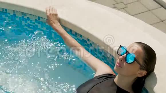 穿着黑色泳衣的女孩躺在街上的一个圆形游泳池里视频的预览图
