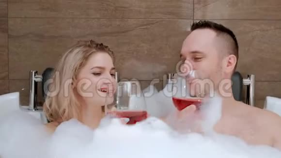 年轻夫妇男人和女人用泡沫躺在浴室里视频的预览图