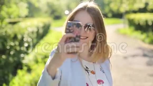 戴墨镜的漂亮女孩用智能手机自拍视频的预览图