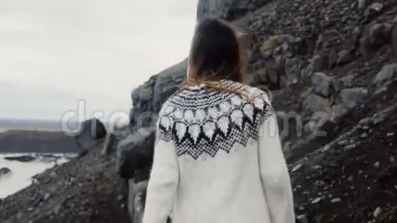 年轻的旅行妇女独自在山上徒步旅行在冰岛的瓦特纳霍卡尔冰湖附近的岩石中行走视频的预览图