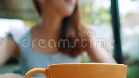 活泼开朗的亚洲年轻女人在咖啡馆里喝着热咖啡或茶享受着它视频的预览图