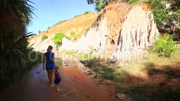 母亲小女孩沿着小溪走到陡峭的悬崖视频的预览图