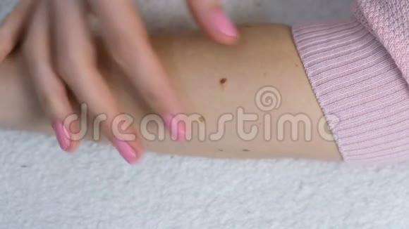 女人正在摸她手上的痣穿着粉红色的毛衣合手视频的预览图
