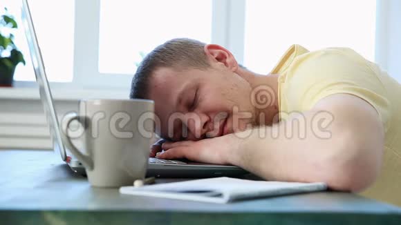 自由职业程序员在带笔记本电脑的办公桌上因疲劳而睡着视频的预览图