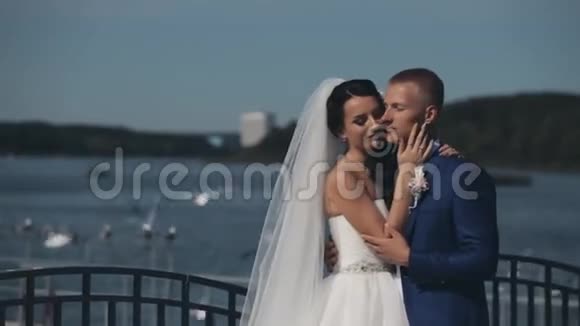 年轻漂亮的夫妇站在河边在他们的婚礼上拥抱新婚夫妇花时间在一起视频的预览图