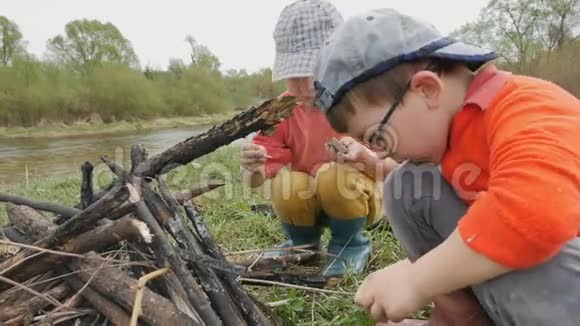 两个小男孩在风景如画的河岸上生火视频的预览图