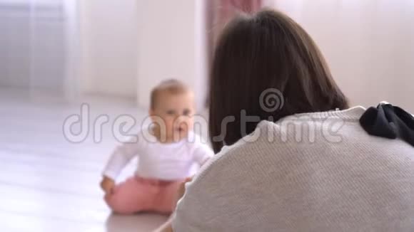 母亲用手机相机拍摄顽皮的女婴视频的预览图