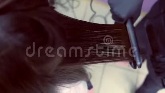 美容师在美容院用发钳给美女扎黑棕色头发头发特写视频的预览图