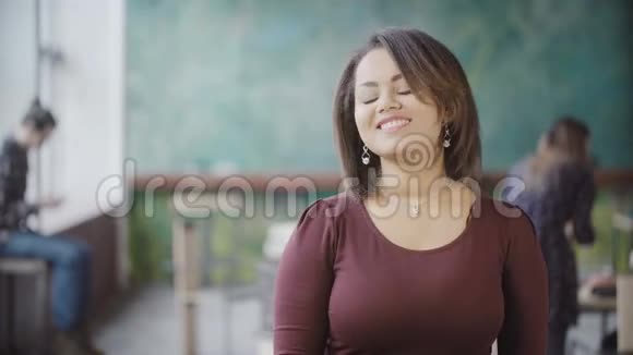 年轻美丽的非洲妇女在繁忙的办公室微笑的肖像女性看着相机亲吻空气视频的预览图