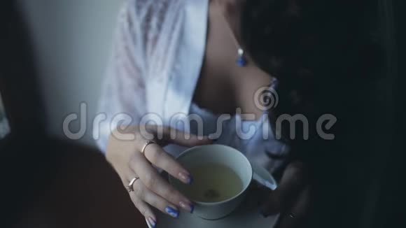 年轻美丽的新娘的早晨女士内衣的近景佩诺阿呆在窗边喝茶视频的预览图