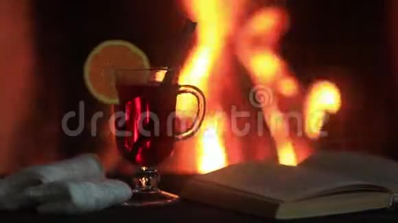 热覆盖葡萄酒和一本书在桌子上背景上有火的壁炉视频的预览图