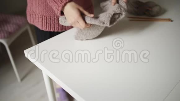 女人期待着宝宝看着躺在桌子上的针织毛衣手工制作的衣服视频的预览图