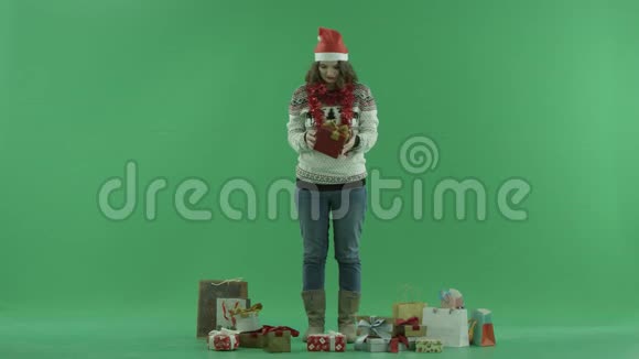 戴着圣诞帽的迷人年轻女子试图意识到她的圣诞礼物盒里有什么背景上的彩色钥匙视频的预览图