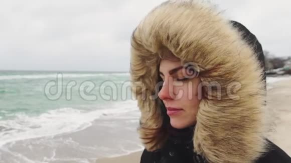 在寒冷的冬天年轻漂亮的女人在海滩上走来走去慢动作视频的预览图
