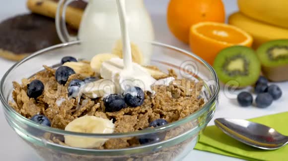 早餐时在谷类食品薄片和水果上倒入牛奶视频的预览图