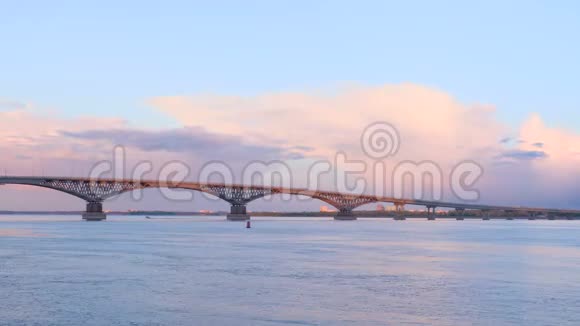 日落时分萨拉托夫和恩格斯两个城市之间一座横跨伏尔加河的公路桥的时间推移蓝天和粉红的云彩视频的预览图