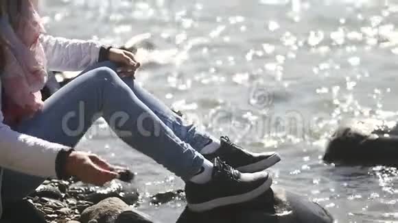 一个年轻的女人把石头扔进水里享受着温暖阳光明媚秋天的一天视频的预览图