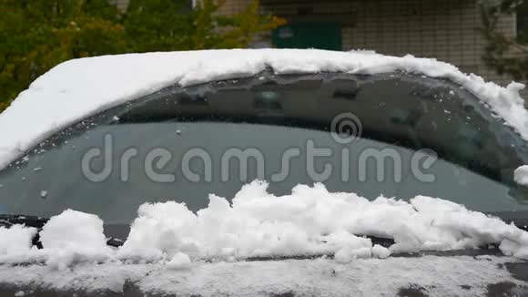 慢镜头拍摄手刮雪从冰冻的汽车挡风玻璃雪花流过太阳视频的预览图