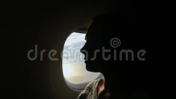 在飞机上旅行飞机窗上一位年轻女子的剪影视频的预览图