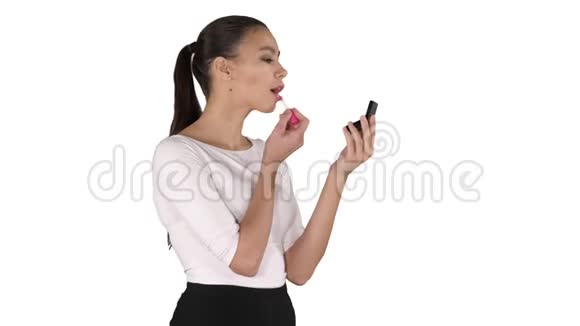 美丽的女人染红她的嘴唇口红粉红色照在镜子上的白色背景视频的预览图