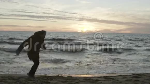 悲伤的人在海边奔跑抛沙美丽的海洋景观海滩上有波浪和日落视频的预览图