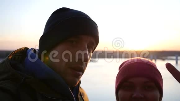 少年夫妇在秋日日落的背景下在河边拍摄在室内展示视频的预览图