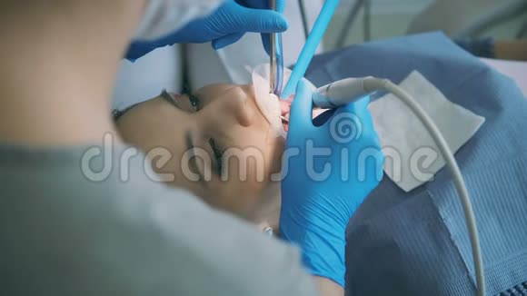 坐在牙科椅上的年轻女人医生治疗病人使用牙科镜和钻孔发动机视频的预览图