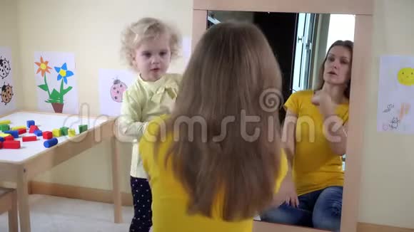 女孩在镜子前梳着女人的头发视频的预览图