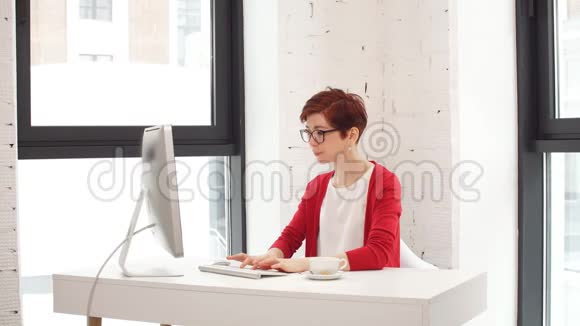年轻妇女在办公室工作坐在办公桌前用电脑看屏幕视频的预览图