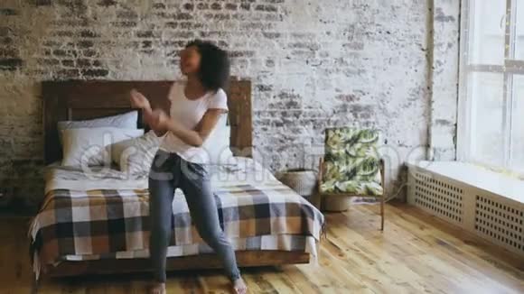 有魅力的混血快乐的女孩在家附近的床上尽情跳舞视频的预览图