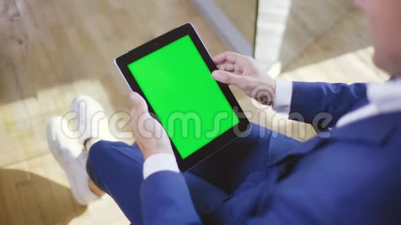 穿着蓝色正式服装的人用平板电脑看网上报纸视频的预览图