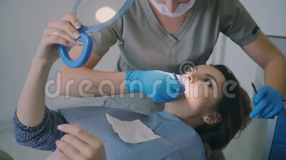 去看牙医的女人女性躺在牙科椅上拿着镜子正畸医生检查过牙伤视频的预览图
