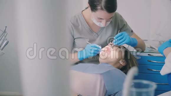 计划的牙科检查当医生治疗病人时女人张开嘴坐在牙医椅上视频的预览图