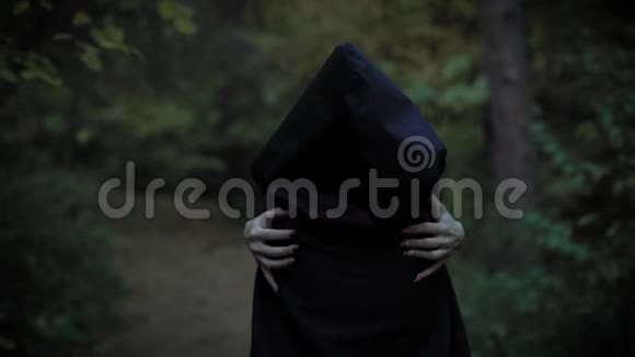 一个披着兜帽的女人用长长的指甲拥抱自己就像一个女巫一个神秘的女人走路视频的预览图