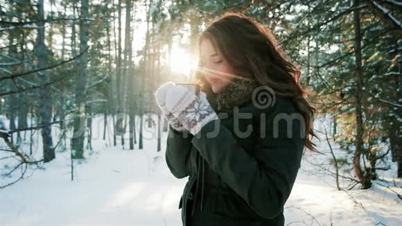 浪漫的女孩在背光的阳光下享受饮料年轻的女人在冬天的森林里喝茶喝咖啡视频的预览图