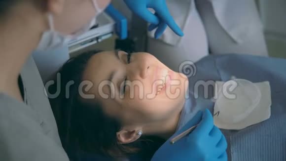 年轻女子坐在牙科椅上和医生交谈当牙医建议时女性微笑和大笑视频的预览图