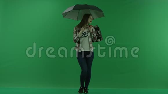 一个肩膀上背着袋子的女孩站在绿色屏幕上的伞下视频的预览图