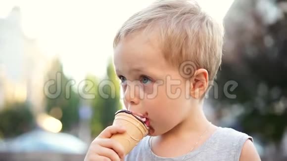 可爱的小男孩在夏天在蛋筒里舔冰淇淋视频的预览图