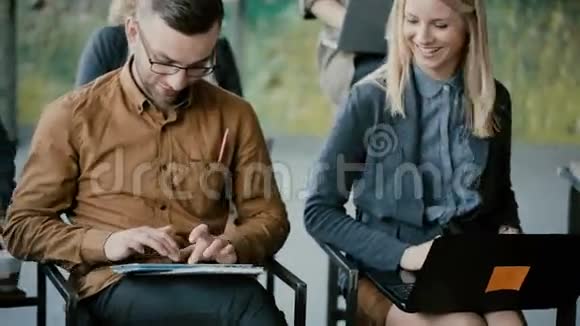 年轻快乐的一群人在商务会议上男人和女人微笑使用小玩意笔记本电脑和数字平板电脑视频的预览图